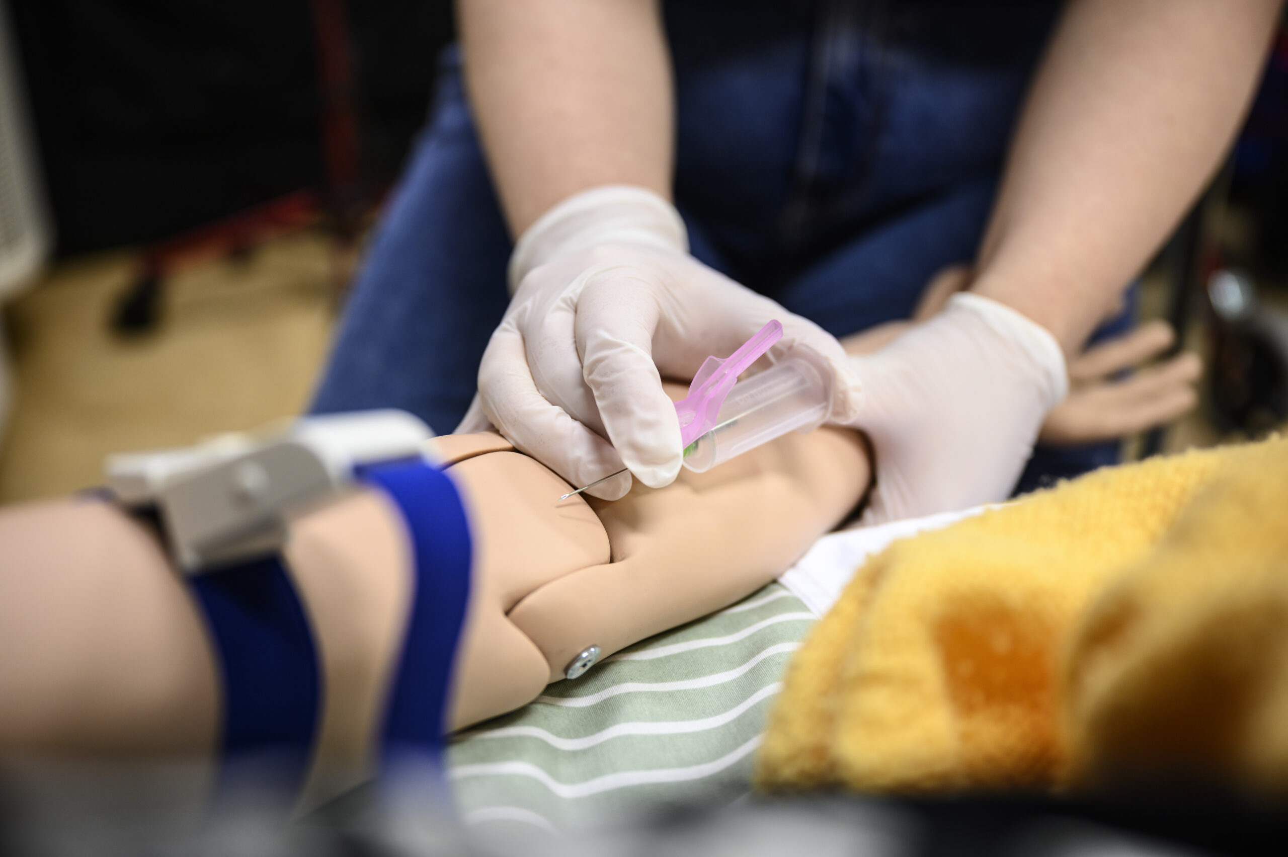 Undesköterskestuderande övar att ta blodprov på en attrapp docka